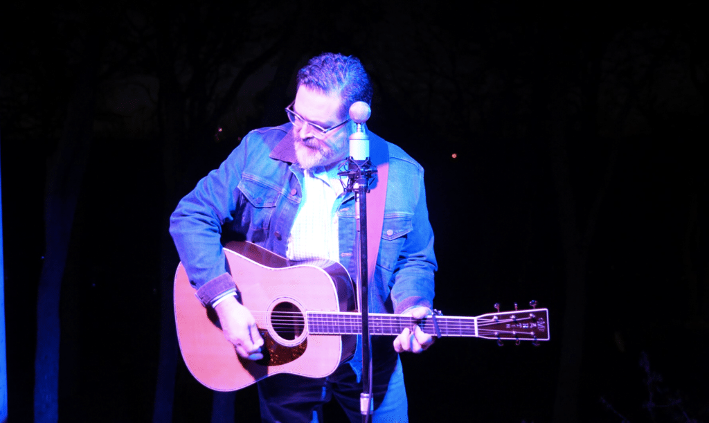 Dan Gonzalez with acoustic guitar and mic performing